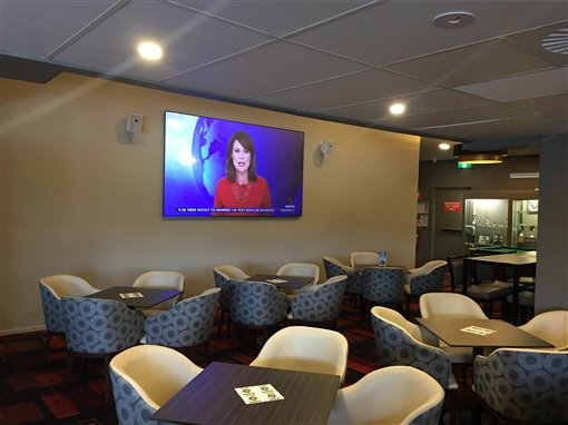 The lounge at Raiders Weston: armchairs around tables and a large wall-mounted TV